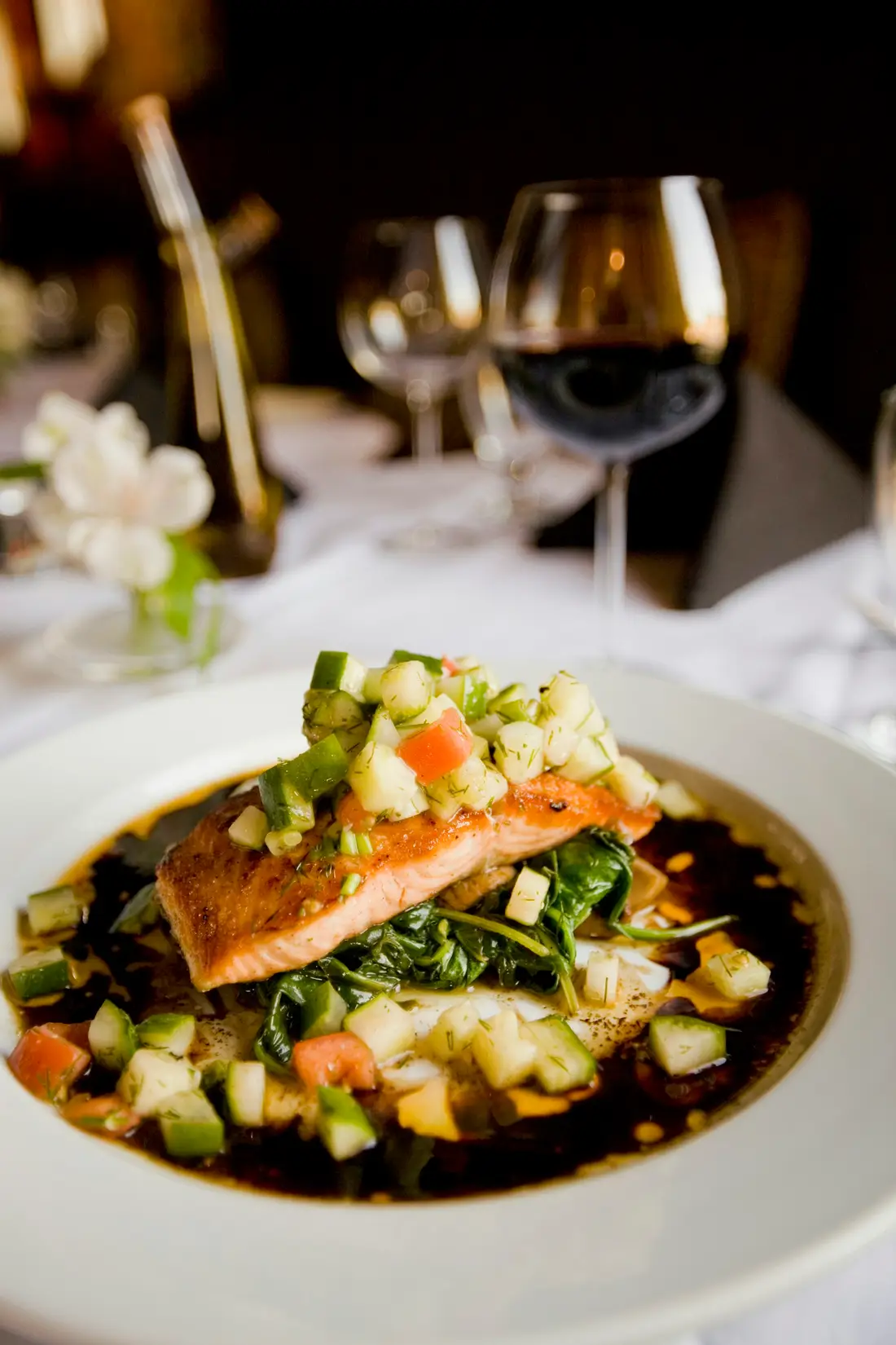 Pan-roasted brook trout over wilted greens, served with a glass of red wine